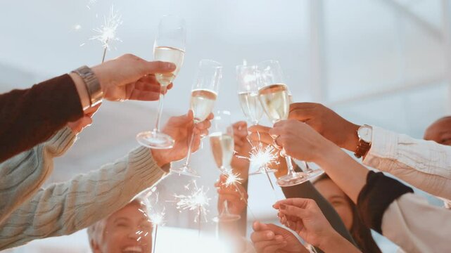Celebration, sparklers and toast with business people at office party together for goals or target. Champagne, cheers and hands of employee team in workplace for achievement, milestone or success