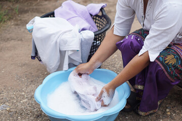 Hand washing clothes in a plastic basin outdoors. Concept, traditional care and patience reflect sustainable living and love through every gentle scrub and soap bubble.                