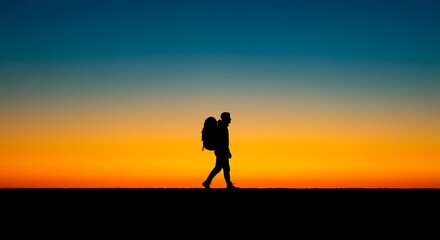 Fototapeta premium Silhouette of Hiker Walking Against Vivid Sunset Sky with Backpack