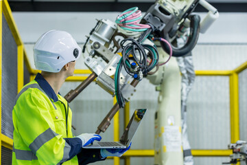 Male and femal engineers checking or maintenance electronic in AI or artificial intelligence Robot, robot arm in the manufacturing automation and robotics manufacture room. Service technical engineer.