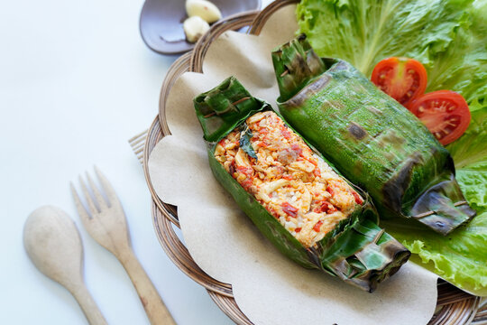 Nasi bakar is an Indonesian food, rice wrapped in banana leaves and then grilled. Rice filled with spices, chili sauce, shredded chicken, meat or fish.