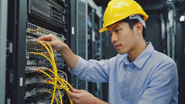 Network Administrator in Data Center: A dedicated network administrator meticulously connects cables within a bustling data center, a modern tech hub, embodying focus and expertise. - Powered by Adobe