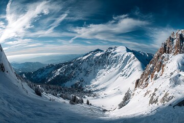 Obraz premium Panoramic vista of snow capped mountains under a blue sky with clouds
