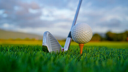 Golf clubs and balls on a green lawn in a beautiful golf course with morning sunshine.
