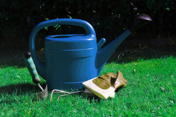 blaue Giesskanne mit Gartenwerkzeug