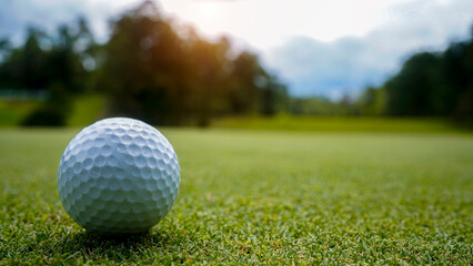 Golf ball on green grass in the evening golf course with sunshine background.