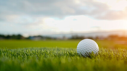 Golf ball is on a green lawn in a beautiful golf course with morning sunshine.