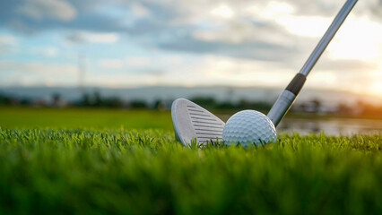 Golf clubs and balls on a green lawn in a beautiful golf course with morning sunshine.