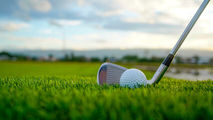 Golf clubs and balls on a green lawn in a beautiful golf course with morning sunshine.