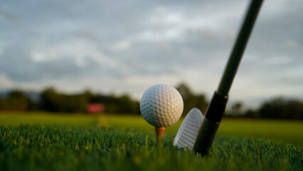 Golf clubs and balls on a green lawn in a beautiful golf course with morning sunshine.