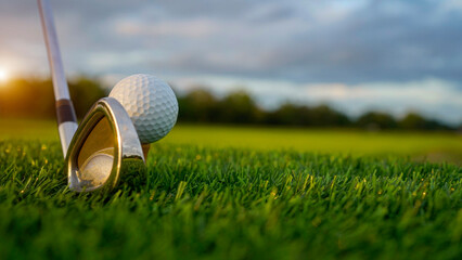 Golf clubs and balls on a green lawn in a beautiful golf course with morning sunshine.