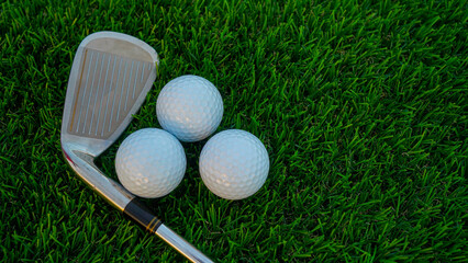 Golf clubs and golf balls on a green lawn in a beautiful golf course with morning sunshine.