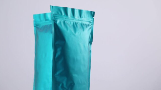 Zipper stand-up pouches spinning on light grey background, closeup. Space for text