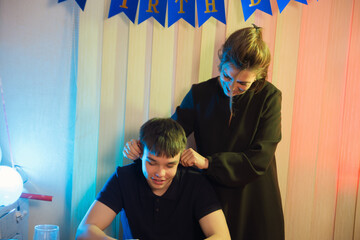 Mother playfully pulls son's ears, a birthday tradition, celebrating together with affection and...