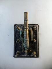 Antique brass artillery cannon still life on a distressed white table with grunge texture background. Top View.