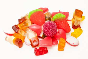 Fruit jelly beans in many colors in a glass bowl on a white background.