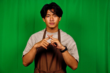 Young Man Wearing Apron Standing in Front of Green Screen Making Heart Gesture
