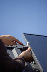 A man is installing solar panels on a roof. Selective focus
