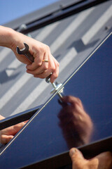 A man is installing solar panels on a roof. Selective focus