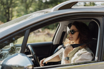 Young woman driver fastening seat belt, car safety travel concept