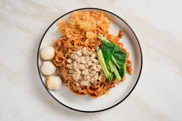 Spicy Asian Chili Oil noodles with minced chicken, fish balls, and vegetables served on plate. Perfect for recipes, articles or any cooking content.