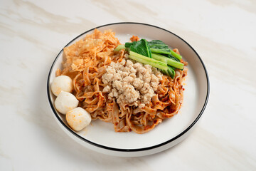 Spicy Asian Chili Oil noodles with minced chicken, fish balls, and vegetables served on plate. Perfect for recipes, articles or any cooking content.