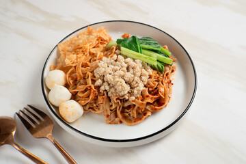 Spicy Asian Chili Oil noodles with minced chicken, fish balls, and vegetables served on plate. Perfect for recipes, articles or any cooking content.