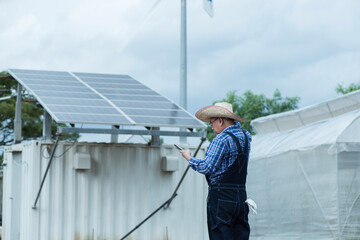 Man with solar panels  and wind turbine on background in smart farm