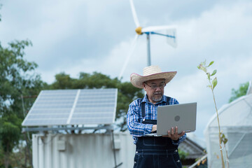 Man with solar panels  and wind turbine on background in smart farm.