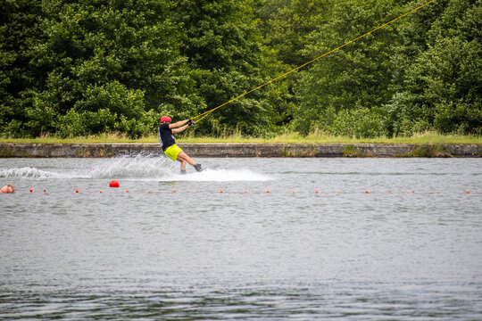 Wakeboarder rides close to the lakeshore, creating a small splash