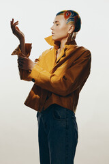 Stylish woman with colorful shaved hairstyle wearing yellow leather jacket and blue jeans poses...
