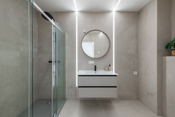 Modern Bathroom With Glass Shower, Vanity Unit, and Circular Mirror