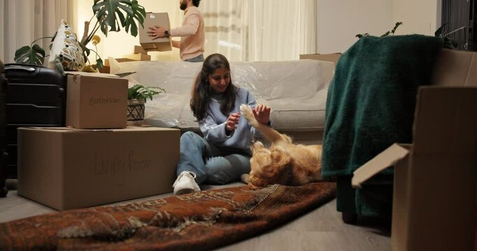 Moving in, woman and playing with dog in new home for property purchase, mortgage loan or security. Homeowners, couple and happy with animal on floor for pet friendly apartment, relocation and goals