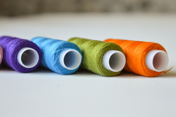 colorful spools of thread lined up on a white surface great for themes like sewing, textile arts,...