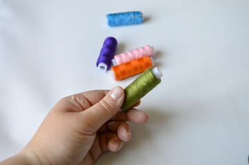 colorful spools of thread lined up on a white surface great for themes like sewing, textile arts,...