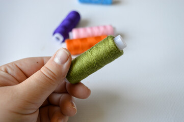 colorful spools of thread lined up on a white surface great for themes like sewing, textile arts,...