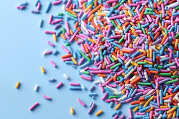 A vibrant mix of colorful sprinkles scattered across a blue surface, perfect for decorating desserts and adding a fun touch to any sweet treat.