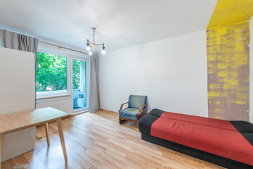 Minimalist Small Living Room Interior With Bed, Wooden Desk, and Natural Light