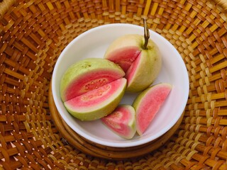 Red-fleshed guava halves sit in a wicker basket.