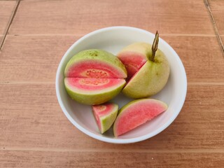 Red-fleshed guava halves are placed together on a plate.