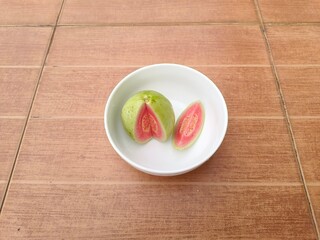 Red-fleshed guava halves are in a cup.