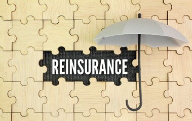 Puzzle, umbrella with the word REINSURANCE. insurance reform concept. an arrangement whereby an insurer transfers all or part of a risk to another insurer to provide protection against the risk of the