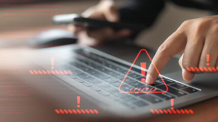 Close-up of businessman's hand pressing laptop keyboard with cybersecurity attack warning,...