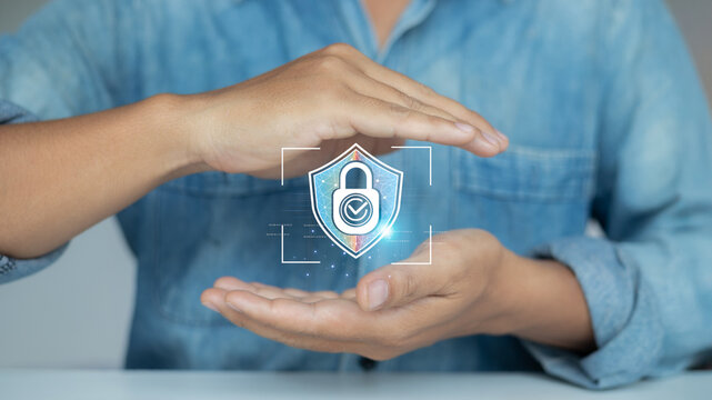 Businessman showing hand gesture protecting digital shield icon, representing data security, cybersecurity protection, and information privacy in digital technology.