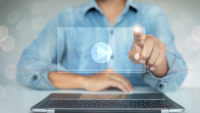 Man pressing virtual play button on laptop screen, representing digital video streaming, online media content, and e-learning technology for business and education.