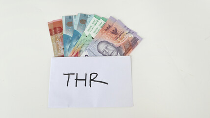 Indonesian Money, rupiah or IDR in envelope with THR Text. Hand holding THR envelope. THR is holiday allowance on Eid al-Fitr or Lebaran days. background white best quality.