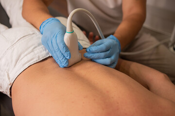 Professional therapist is giving a massage with a machine on the patient back