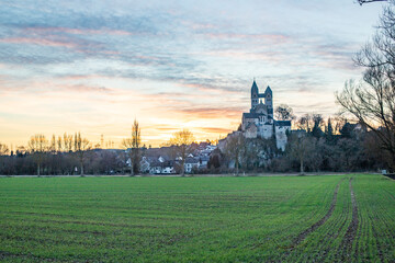 A winter landscape shot at sunrise. Plenty of nature and a large church on a rock. The former collegiate church of St. Lubentius Limburger, Dietkirchen, Hesse