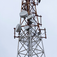 Telecommunication tower standing tall against overcast sky with various antennas for signal...