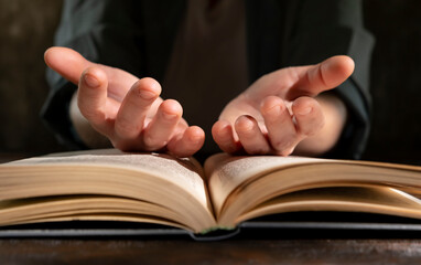 Hands reaching out from a book on a wooden table, symbolizing connection and communication